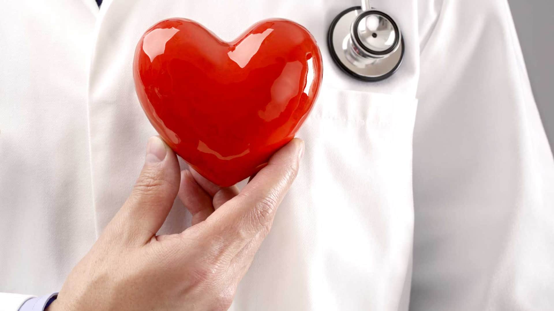 Médico sostiene un corazón rojo junto a su estetoscopio