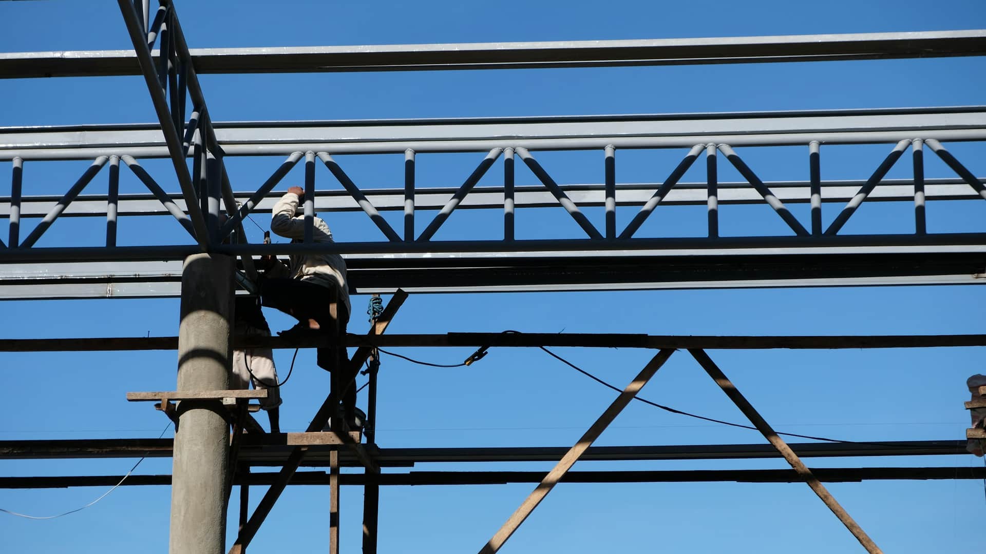 Trabajador con arnés de seguridad sobre una viga de acero en altura